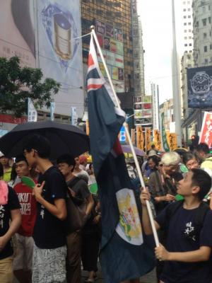 A marcher waves the colonial-era Hong Kong flag during the democracy march organized by Civil Human Rights Front, Hong Kong, July 1, 2015. HRIC photo.